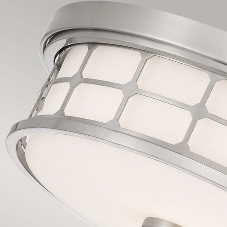 Close-up of the Guardian 2 Light Flush ceiling light fixture featuring a brushed nickel frame with a hexagonal pattern. The opal glass shade emits a soft glow, enhancing its sleek and contemporary design against a plain gray background.