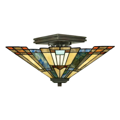 The Inglenook 2 Light Tiffany Semi-Flush in Valiant Bronze displays an Art Deco design with a stained glass shade featuring geometric patterns in shades of green, orange, blue, and cream. The light is mounted on a metal base and gently diffuses through the colored panels, creating an Arts & Crafts style ambiance.