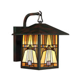 The Inglenook Outdoor 1 Light Medium Wall Lantern in Valiant Bronze features a stained glass shade in shades of amber, cream, and brown. The lantern showcases a rectangular shape with an Arts & Crafts style design and is mounted on a gracefully curved arm.