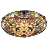 The Kami 2 Light Tiffany Flush in Vintage Bronze is a round stained glass ceiling light displaying intricate floral patterns in shades of brown, green, and cream. The design incorporates geometric shapes and jewel-like accents, producing a warm and elegant glow.