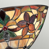 A close-up of a stained glass lampshade featuring the Kami 2 Light Tiffany Wall Light in Vintage Bronze, with an Art Nouveau floral pattern composed of earth-toned petals and deep red accents. The glass pieces form a mosaic of vibrant shapes, evoking the style of a classic Tiffany wall light.