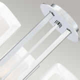 Close-up of the Kolt 3 Light Wall Light in polished chrome, showcasing its modern design with a sleek, dual-glass feature. The fixture comprises polished chrome rods supporting a round metal base with a silver finish, set against a neutral gray background. This light is perfect for enhancing any space with its minimalist charm and elegance.