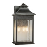 The Livingston Outdoor 3 Light Large Wall Lantern in Imperial Bronze showcases a rectangular shape with seedy glass panels. Inside, three light bulbs create a warm glow, enhanced by a decorative top design for an elegant touch.