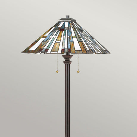 Introducing the Maybeck 2 Light Tiffany Floor Lamp in Valiant Bronze, showcasing a stunning stained glass shade with geometric patterns in blue, white, and amber. This elegant art glass lamp features a dark metal stand and two pull chains for easy light control.