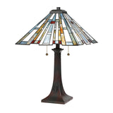 Introducing the *Maybeck 2 Light Tiffany Table Lamp - Valiant Bronze*, featuring a stunning stained glass shade adorned with geometric patterns in blue, yellow, red, and white. This lamp is elegantly designed with a valiant bronze stand and convenient pull chains for easy operation.