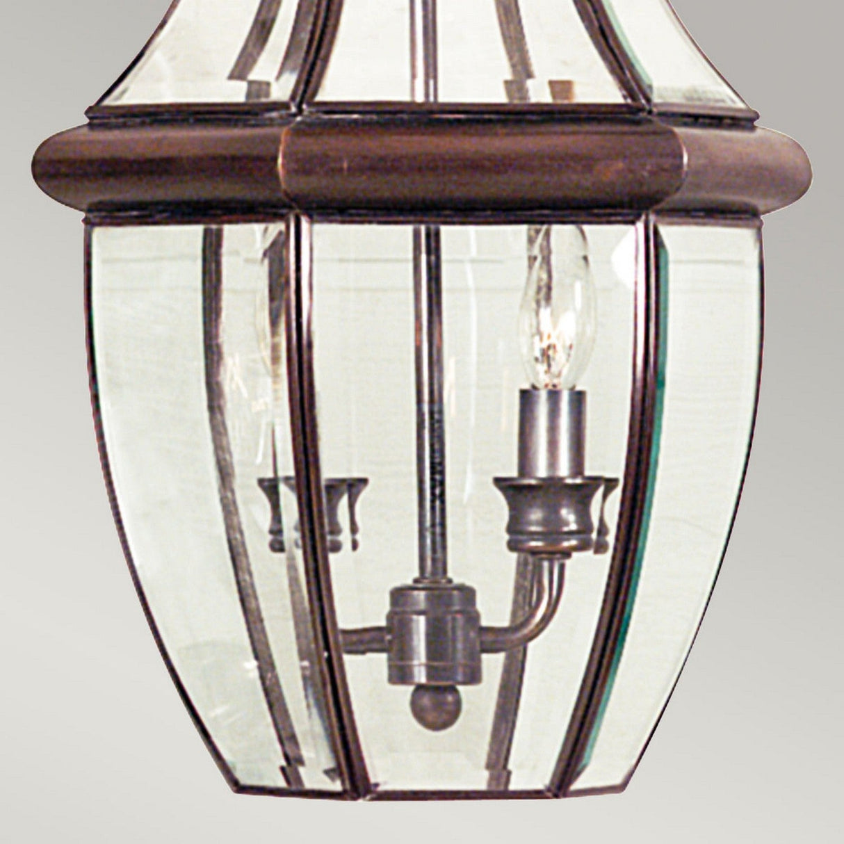 Close-up of the Newbury Outdoor 2 Light Large Chain Pendant, featuring a vintage-style metal frame and clear beveled glass panels. The pendant showcases a classic design with its lacquered aged copper finish, set against a soft gray background that complements its outdoor chain pendant setting.