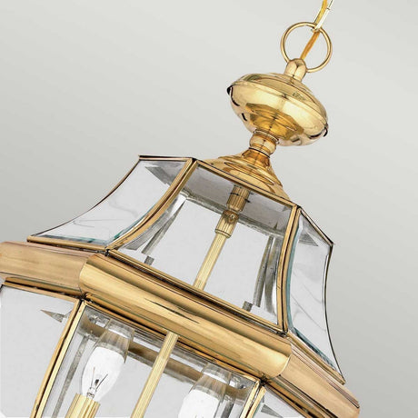 An up-close look at the Newbury Outdoor 2 Light Large Chain Pendant in lacquered polished brass, featuring clear beveled glass panels and a sophisticated design against a neutral backdrop.