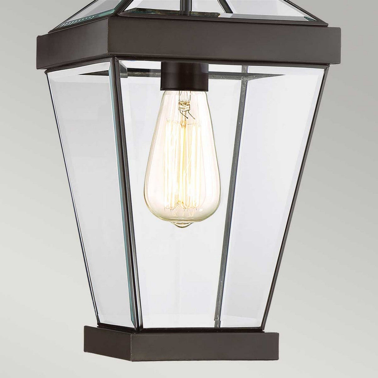 The product features a detailed view of the Ravine Outdoor Medium Chain Pendant in Western Bronze, showcasing its vintage-style design with clear beveled glass panels and a visible filament bulb. The black metal frame, finished in Western Bronze and featuring an angular design, adds a modern yet classic touch.