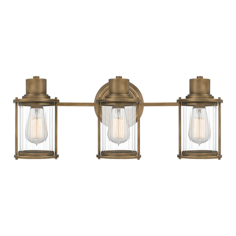 Riggs 3 Light Wall Light in Weathered Brass features a trio of ribbed glass shades with exposed bulbs, supported on a horizontal brass bar and secured to a round backplate.