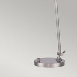 Introducing the Spencer LED Table Lamp - Brushed Nickel, featuring a modern design with a metallic base, circular foundation, and single vertical rod. It includes a convenient side knob on the base for adjusting the dimmer. Presented against a simple light gray background.