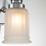 Close-up of the Swell 1 Light Wall Light - Polished Chrome, highlighting its brushed metal wall sconce with a frosted glass shade. The lit lamp emits a warm glow, casting soft shadows against the white background and beautifully displaying its modern, minimalist design and IP44 rating.