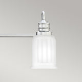 The Swell 3 Light Wall Light in Polished Chrome features a frosted white glass shade designed to resemble a classical column, making it the ideal choice for enhancing bathroom vanities. It casts a gentle, ambient light against the plain light gray background.