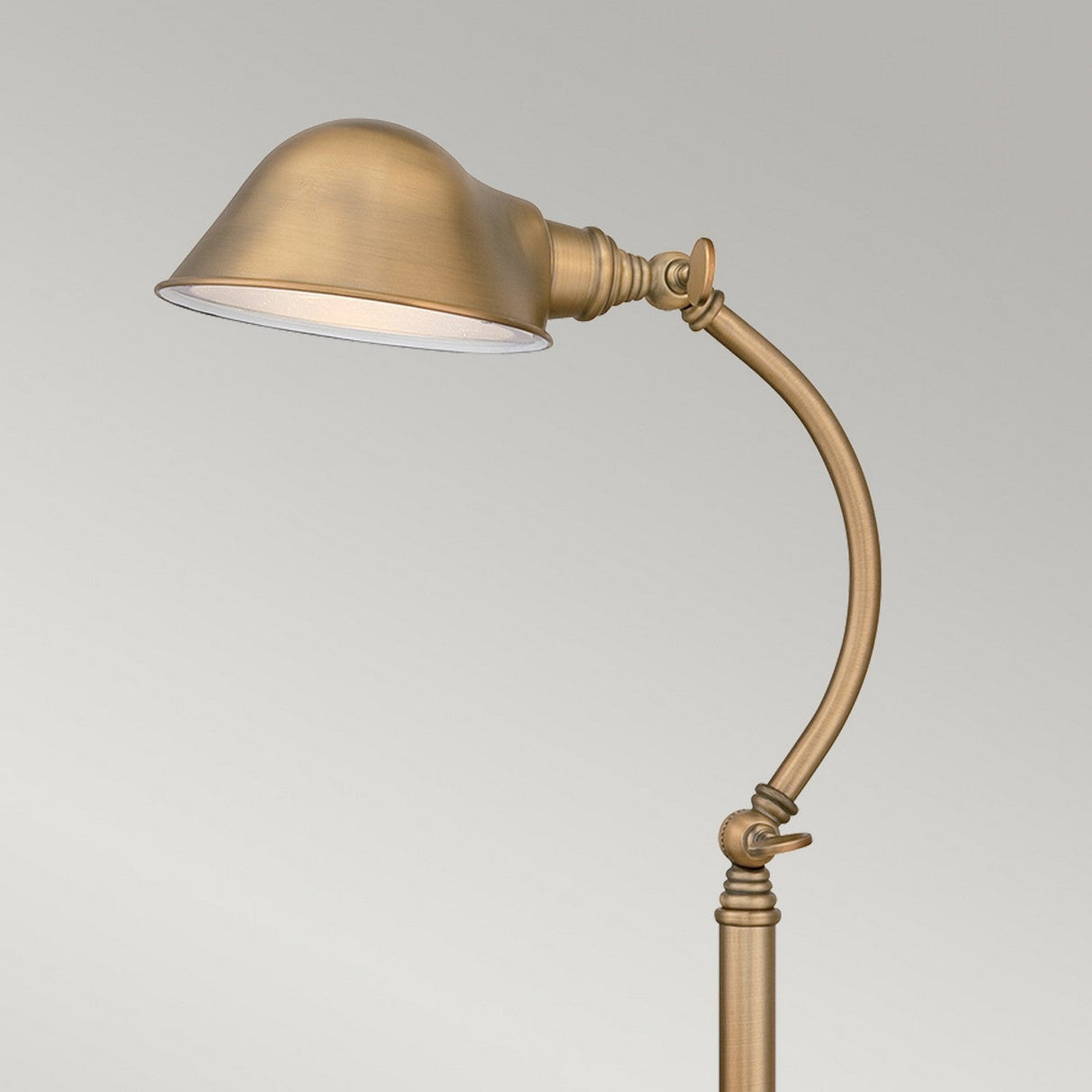 The Thompson LED Table Lamp in aged brass offers a vintage aesthetic with its adjustable curved arm and dome-shaped shade, ideal for illuminating your space against a neutral backdrop.