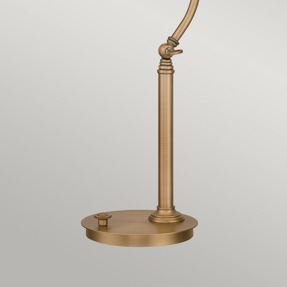 The Thompson LED Table Lamp in aged brass boasts a minimalist design with an adjustable neck and lamp head, complemented by a round base. Its warm metallic finish adds an elegant and modern touch, making it ideal for a study or office setting.