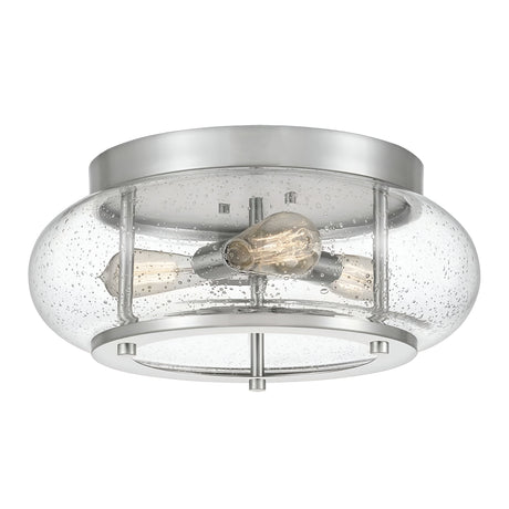 The Trilogy 3 Light Flush - Brushed Nickel is a modern ceiling light fixture that features a brushed nickel base and a clear, seeded glass cover housing two exposed Edison-style LED bulbs, blending industrial and contemporary designs.