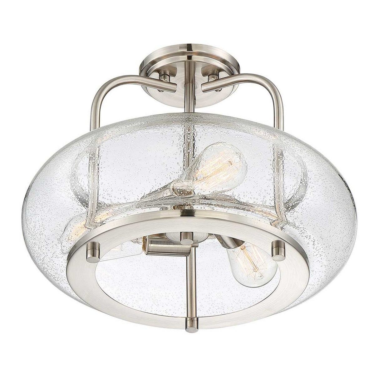 The Trilogy 3 Light Semi-Flush - Brushed Nickel is a modern ceiling light fixture that showcases a circular brushed nickel frame paired with a clear, seeded glass shade. It accommodates three visible LED filament bulbs, delivering a contemporary and stylish appearance.