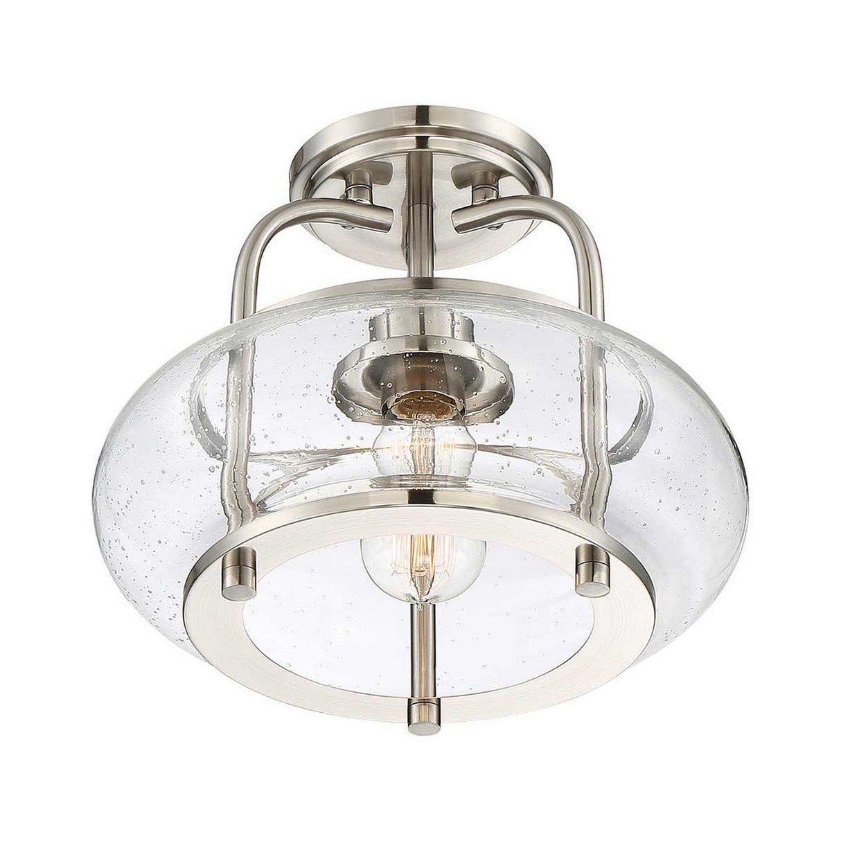 The Trilogy 1 Light Semi-Flush in Brushed Nickel features a modern design with a brushed nickel finish. It boasts a clear, seeded glass bowl-shaped shade adorned with tiny bubbles, which elegantly reveals an Edison-style LED filament bulb inside.