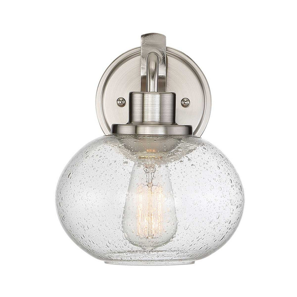 The Trilogy 1 Light Wall Light - Brushed Nickel boasts a brushed nickel base paired with a clear, seeded glass globe shade. An Edison-style bulb inside emits a warm glow through the unique textured water droplet pattern.