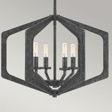 The Vanguard 4 Light Chandelier - Old Black showcases a modern hexagonal frame made from geometric black metal, featuring four exposed vertically aligned bulbs. Its industrial-inspired design stands out against a simple light gray background.