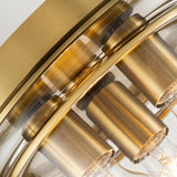 Close-up of the Whistling 3 Light Flush in brushed brass, featuring visible bulbs. The design includes cylindrical brass holders and a curved glass cover, presenting a modern and elegant aesthetic. Ideal for bathroom lighting with its IP44 rating.
