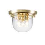 The Whistling 3 Light Flush - Polished Brass is a modern ceiling light fixture featuring a polished brass finish and a clear glass dome, ideal for bathroom lighting. It showcases three exposed bulbs, providing a sleek and contemporary look.