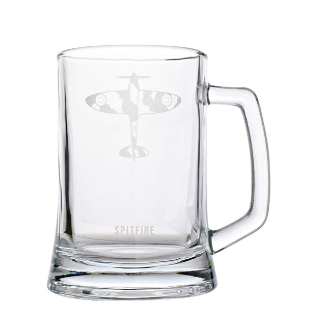 Clear glass tankard beer glass with handle, etched with an overhead Spitfire aircraft silhouette and camouflage markings, "SPITFIRE" text below, on a plain white background.