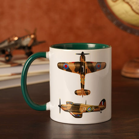 Hurricane Stoneware Mug 11oz, white ceramic with green interior and handle, printed with top and side views of a camouflaged Hurricane fighter plane, displayed on a desk.