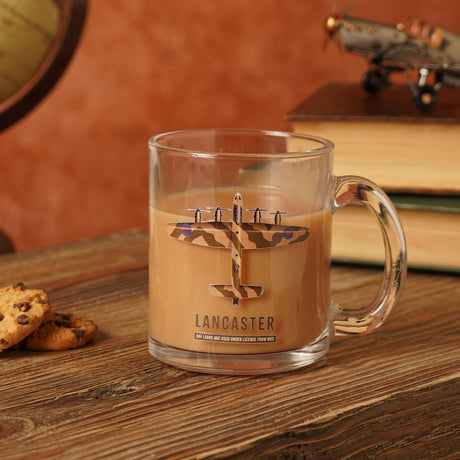 Clear glass mug filled with coffee, printed with a camouflage Lancaster bomber design and "LANCASTER" text, shown on a wooden surface with books and cookies.
