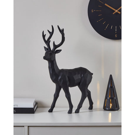 Ransiki Stag Ornament 44cm in black faceted polyresin, standing mid-stride with branching antlers, displayed on a white sideboard beneath a wall clock.