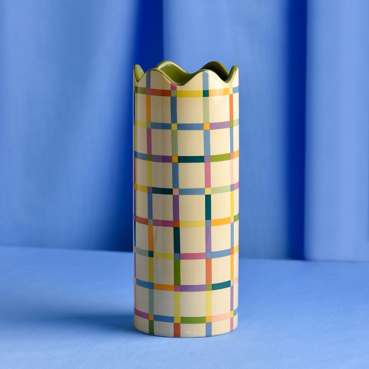 Cylindrical ceramic vase, 25.3cm tall, with a multicoloured check pattern in blue, pink, orange, green and purple on yellow, finished with a wavy green rim.