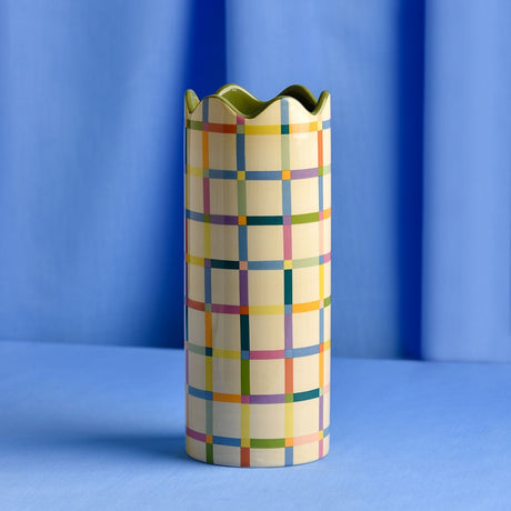 Cylindrical ceramic vase, 25.3cm tall, with a multicoloured check pattern in blue, pink, orange, green and purple on yellow, finished with a wavy green rim.