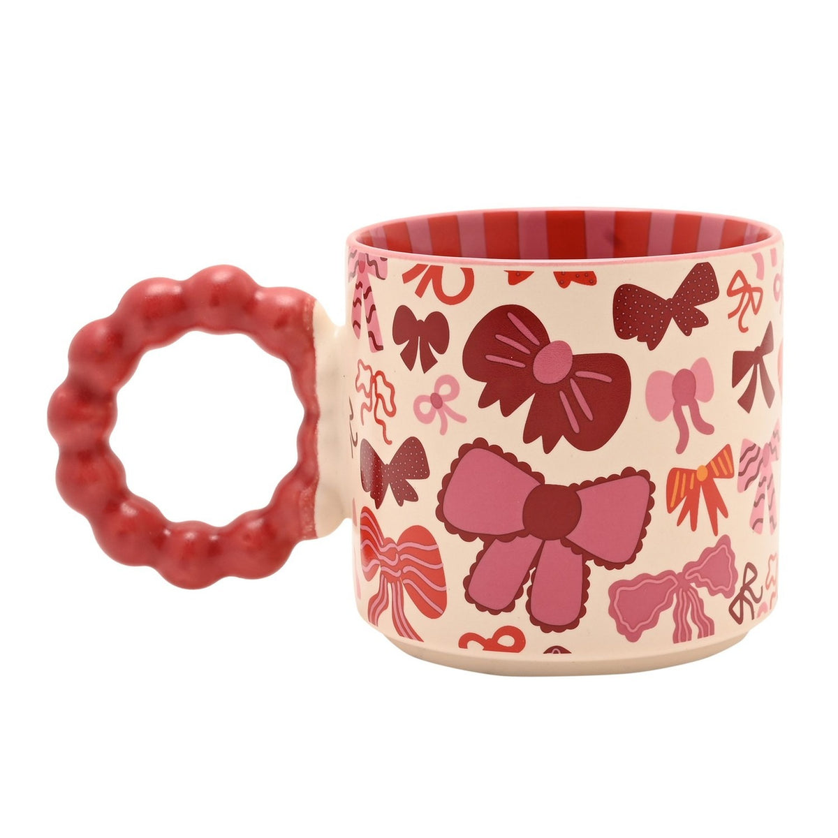 Porcelain mug in cream with a red and pink bows pattern, chunky red beaded ring handle, and red striped interior, shown on a white background.