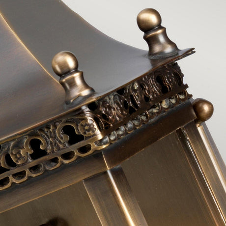 Close-up of the Regents Park 1 Light Outdoor Wall Light in aged brass, showcasing its intricate scrollwork and decorative finials. The patina on the metal surface accentuates its detailed craftsmanship, and its IP44 rating guarantees durability.