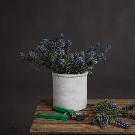 Hill Interiors Small Lavender Spray with purple florets and grey-green foliage arranged in a white ceramic pot on a wooden table with green secateurs.
