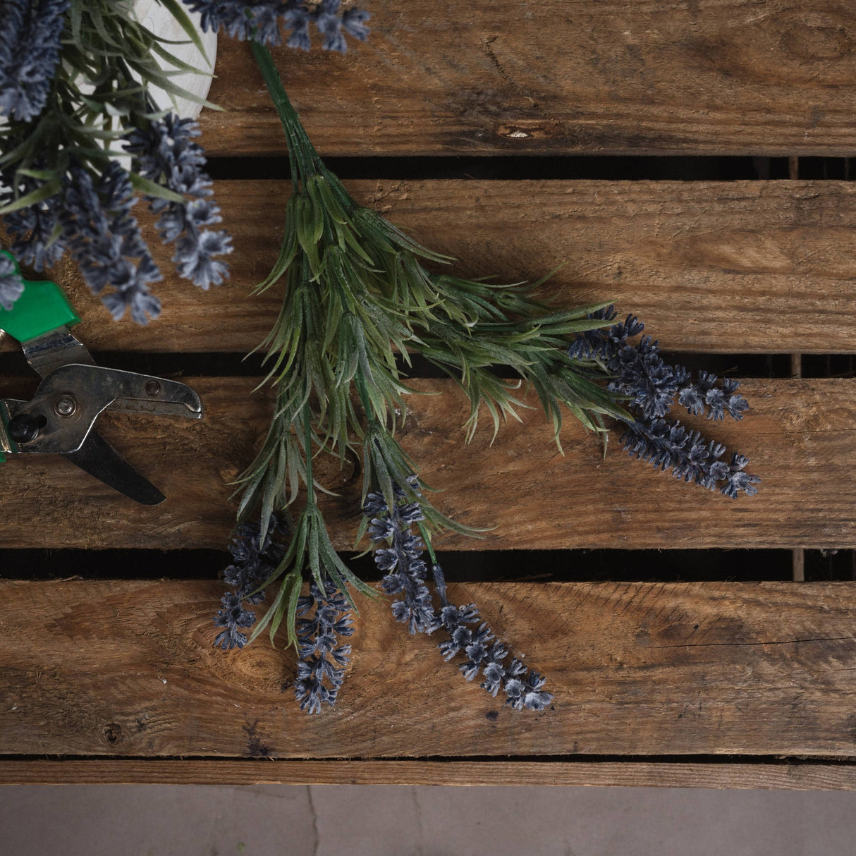 Hill Interiors Small Lavender Spray with purple florets and grey-green foliage laid on a rustic wooden pallet beside metal snips and further lavender stems.