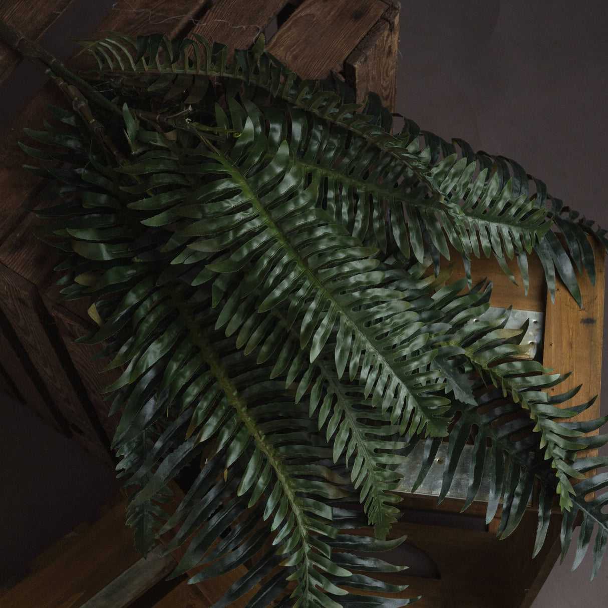 Hill Interiors Fern Bunch faux foliage with layered green fronds and serrated leaves, arching over a rustic wooden crate.