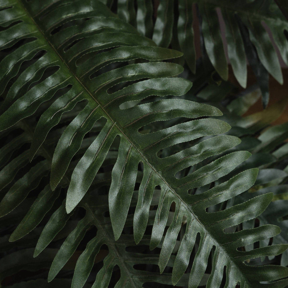 Close-up of Hill Interiors Fern Bunch faux foliage showing layered green fronds with fine serrated edges and subtle tonal variation across the leaves.