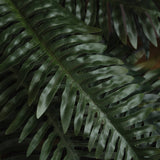 Close-up of Hill Interiors Fern Bunch faux foliage showing layered green fronds with fine serrated edges and subtle tonal variation across the leaves.