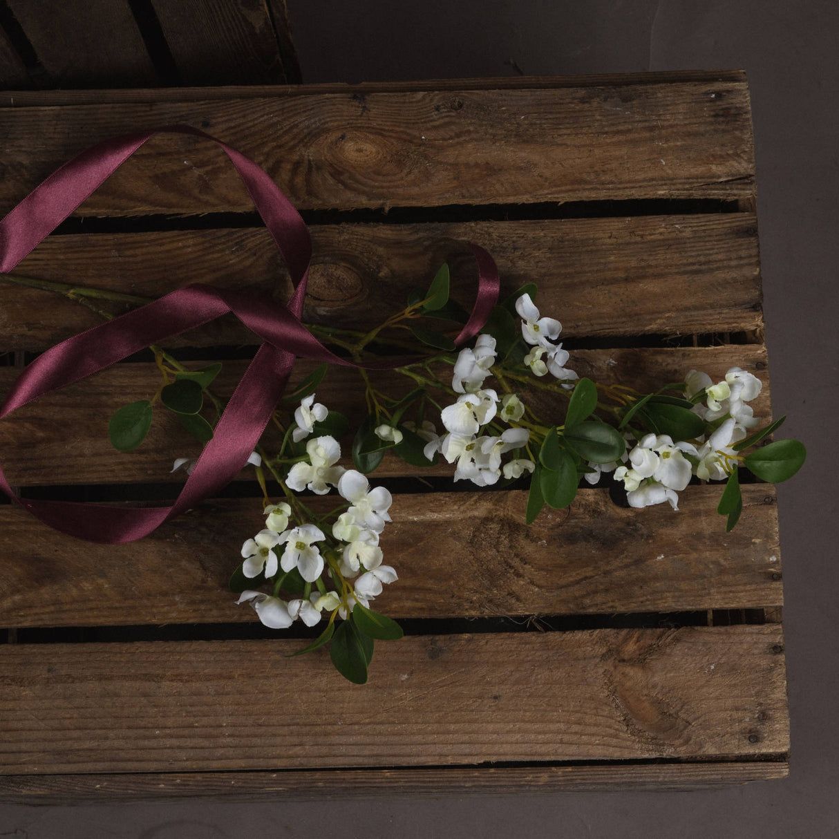 Hill Interiors White Spring Mock Orange Flower stem with cupped white blooms and green leaves, laid on a rustic wooden crate with burgundy satin ribbon.