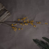 Hill Interiors Forsythia faux flower stem with clusters of yellow four-petalled blooms on woody branches, laid on grey with a wooden crate and fern.