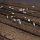 Hill Interiors Pussy Willow Branch faux foliage stems with soft white downy buds along slim green branches, laid across rustic dark wooden planks.