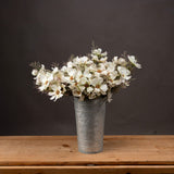 Cream Cosmos Spray by Hill Interiors arranged with fine foliage in a tall galvanised metal florist bucket on a wooden surface against a dark grey background.