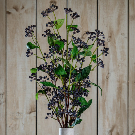 Hill Interiors Viburnum Berry faux foliage stem with clusters of matte dark blue berries and veined green leaves, displayed against a wooden plank backdrop.