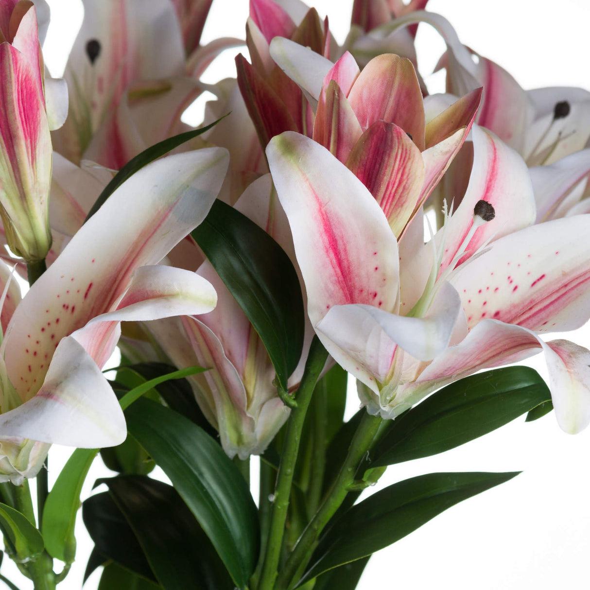 Close-up of Hill Interiors Stargazer Lily faux stem showing white petals with pink centres, speckled detailing, dark stamens and green leaves.