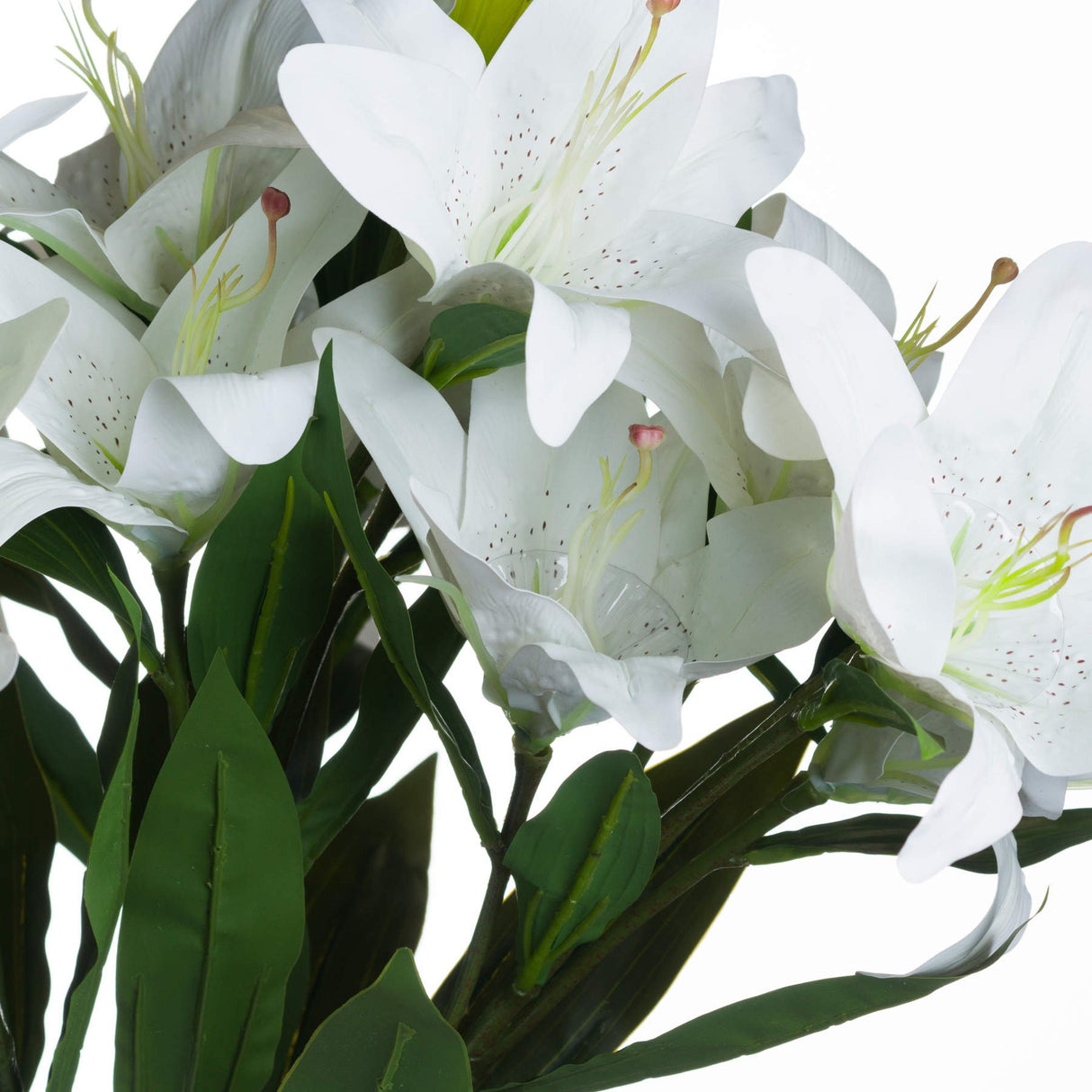 Close-up of Hill Interiors White Lily faux stem showing matte petals with speckled centres, slender stamens, pink-tipped buds and veined green leaves.