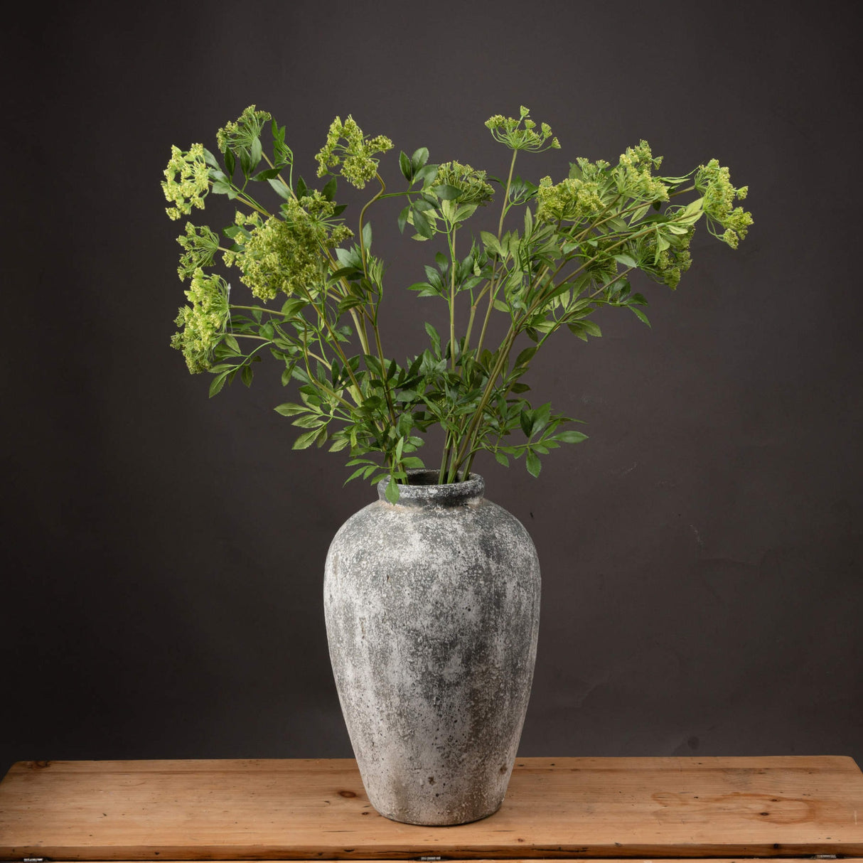 Hill Interiors Faux Cow Parsley Ammi stems with airy green florets and feathery foliage arranged in a weathered stone vase on a wooden surface.
