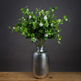 Hill Interiors Cream Gardenia Stems arranged in a ribbed silver vase on a wooden surface against a dark grey background.