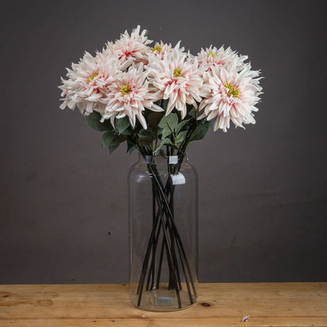 Hill Interiors Lush Pink Dahlia faux stems arranged in a tall clear glass vase on a wooden surface against a dark grey background.