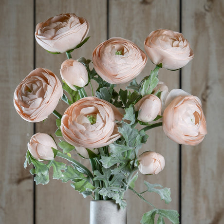 Hill Interiors Pastel Pink Ranunculus faux stems with layered blooms and buds among soft green foliage, arranged in a pale vase against timber panelling.
