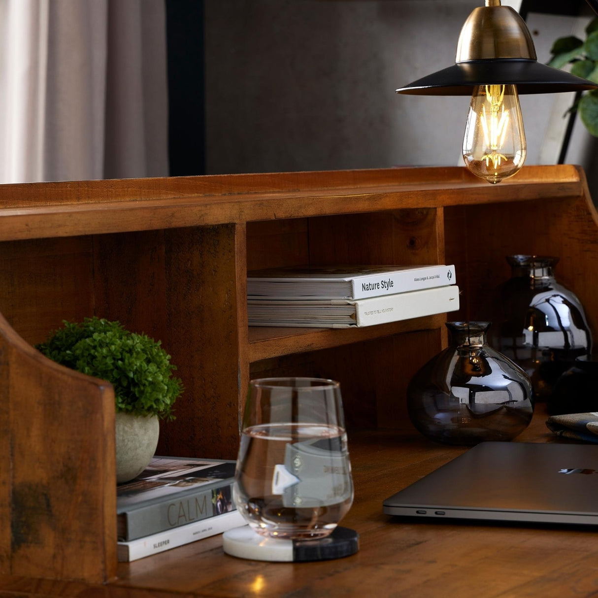 Hill Interiors Miniature Hebe Veronica In Pot styled on a wooden desk with books, glassware, a laptop and a brass pendant light above.